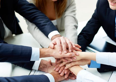 Close-up of business partners making pile of hands at meeting